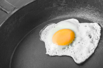scrambled eggs in a cast iron skillet. Isolated on dark painted wood from above.