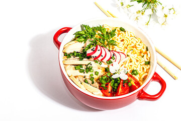 Asian noodles with chicken, vegetables, and herbs are isolated on a white background