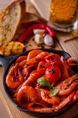 Shrimps fried in soy sauce with cherry tomatoes and a sprig of basil and a glass of beer