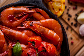 Shrimps fried in soy sauce with cherry tomatoes and a sprig of basil and a glass of beer