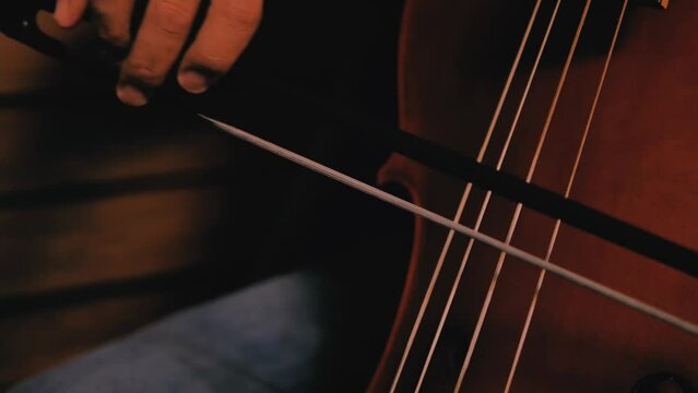 Closeup of man's hand playing cello. Baroc cello played holding the bow. Detail of vibrating cords.