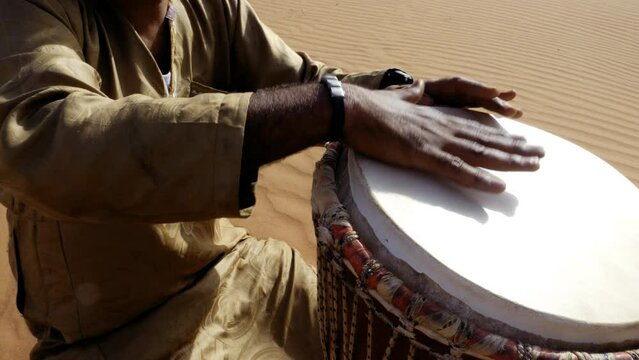 A Moroccan man plays a traditional djembe drum in the desert. Nord-African traditional music is often played in the desert and on festivals. 4k