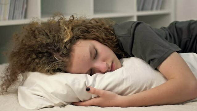 Distressed introvert teen 13s girl child lies on bed at home suffer from school discrimination or bullying problems. Unhappy sad teenager stressed with psychological troubles. Loner, outcast concept.