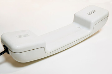 Closeup of a white corded telephone handset on white background. Communication concept.
