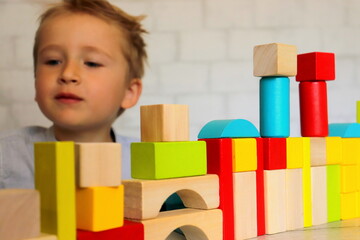 children's wooden geometric shapes multicolored close-up on the table and baby boy in the...