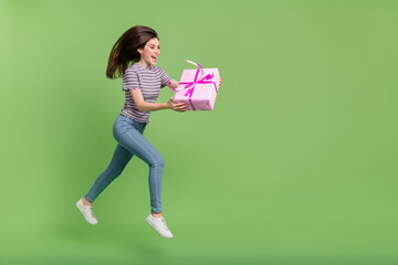 Full length profile portrait of excited pretty lady hold giftbox look empty space isolated on green color background