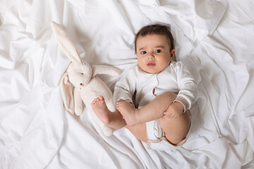 cute little boy laying on blanket with plush rabbit toy , card, banner, health