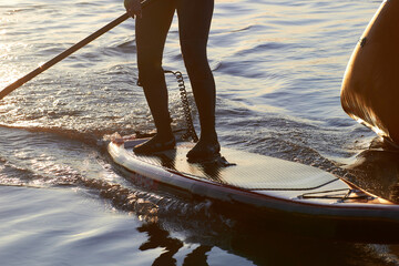 Close up of fragment man's legs on SUP (stand up paddle board) in the Danube river at cold season....