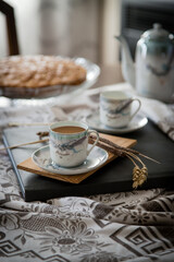 Breakfast or coffee break accompanied by homemade almond cake in a rustic, intimate and cozy atmosphere. Coffee served and ready to drink in cups crafted on an ornate table.