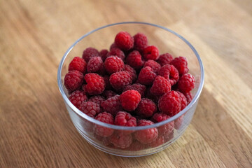 A bowl of fresh raspberry on the wooden table