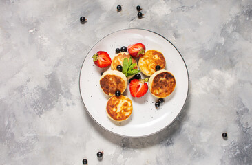 Cottage cheese pancakes, ricotta fritters or syrniki with currant and strawberries. Healthy and delicious breakfast.