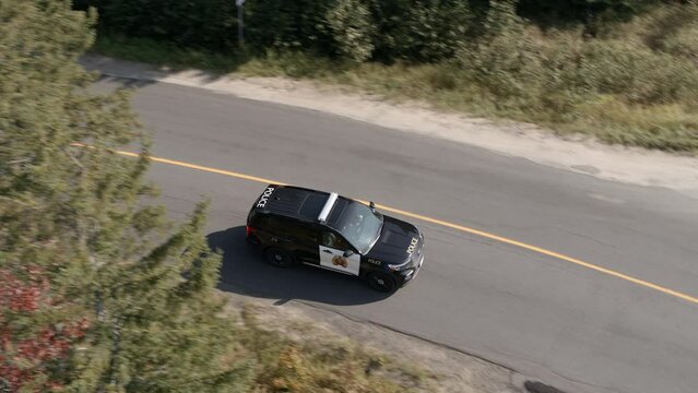 Police Car Driving Along Road In Forest, Ontario, Canada