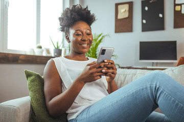 Woman using smartphone at home. Mixed race girl looking at mobile phone. Communication, leisure,...