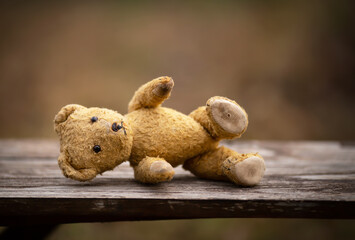 Old toy lying on a bench. Child adoption, abortion or help, hope concept.