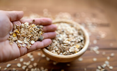 Hand holding muesli cereals. Healthy vegetarian or fitness diet food, breakfast on brown wooden background.
