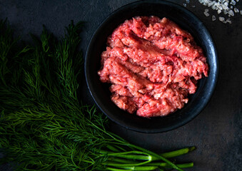 Fresh Raw mince, Minced beef, ground meat with herbs and spices on black plate