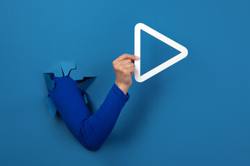 hand holding play button over blue background