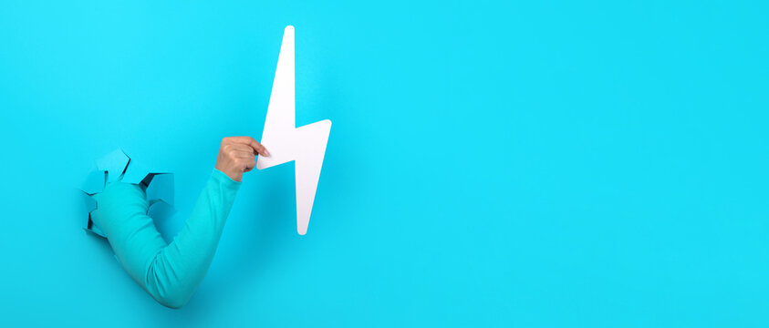 Hand Holding Lightning Bolt Over Blue Background, Panoramic Layout