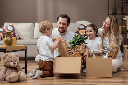 A family sits on the floor unpacking boxes in their new home after moving.
