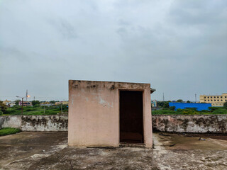 Stock photo of small shelter or room for stairs in the terrace, painted with light orange color. empty residential building terrace, dark cloud, buildings and empty landscape on background.