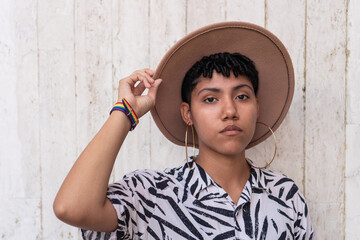 Portrait of confident non-binary person holding a hat. - obrazy, fototapety, plakaty