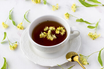 Healing lime tea in a white cup on a white background. Healthy tea