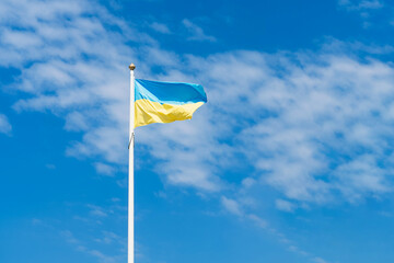 Flag of Ukraine against a blue sky with clouds. 