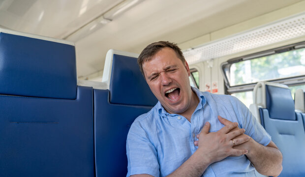 Alone Caucasian Millennial Man Suffering From Heart Attack In Public Transportation. Middle Aged Man On Seat In Subway Train And Suffering From Chest Pain, Pressing On Chest, Closed Eyes