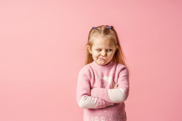 cute little Caucasian girl of 5 years old, insulted and offended on a pink background. The baby is tired, capricious and turns away. Does not make contact. Close-up