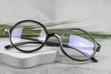 Fototapeta na wymiar Stylish round glasses for vision on a beige podium, close-up