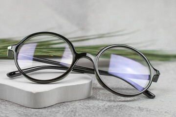 Stylish round glasses for vision on a beige podium, close-up