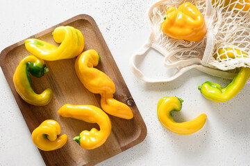 Fresh homegrown ugly organic yellow peppers in mesh bag on white background. Natural vegetables...