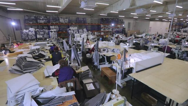 Women in the sewing industry. Large sewing production. There are many seamstresses in the workshop. Garment factory interior.