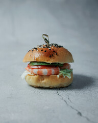 Delicious hot burger on a gray background. Isolate on a gray background. Delicious lunch, snack, food for young people