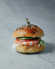 Delicious hot burger on a gray background. Isolate on a gray background. Delicious lunch, snack, food for young people