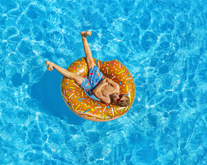 boy with cool rubber ring in swimming pool. Summer holiday party time.