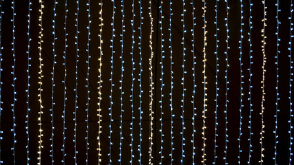 Bottom view of many small light bulbs, festive garland illuminating night sky. Concept. Multicolored street garland stretched against the black night sky. - obrazy, fototapety, plakaty