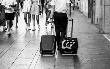 the person walking on the street with two trolleys.