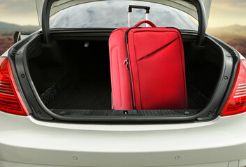 Red suitcase in car trunk and free space for your decoration. 
