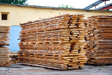 Wood boards piles stored outdoor, lumber storage. Stacked wooden boards at lumberyard. Stack of lumber at outdoor warehouse. Stockpiled boards.