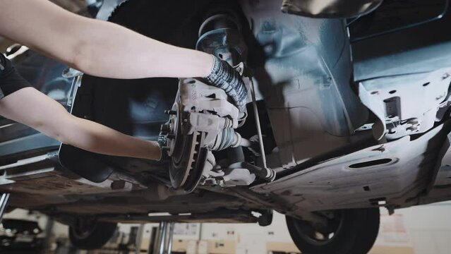 A mechanic at a service station checks the brake and steering systems.