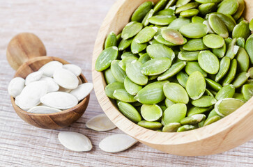 The Organic pumpkin seeds in wooden bowl on wooden table.