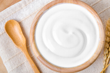 The Greek yogurt in a wooden bowl and dry barley on table.