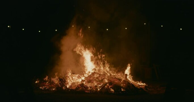 Big bonfire outdoors at night in slow motion. Controlled fire on San Juan party. Burning firewood outside. 