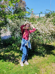 Smiling girl trying on a blooming wreath from a white bush in a sunny garden. Spring mood. Blooming garden.