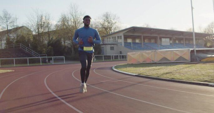 Young black athlete on running track with sunset in the background.
