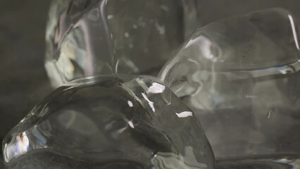Transparent ice cubes rotate on a dark background - Powered by Adobe