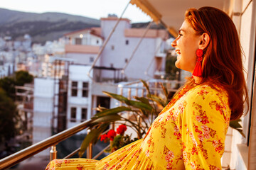 young pretty woman on balcony resting at sunset, lifestyle people concept