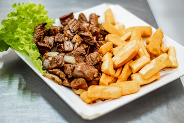 Portion of noble meat with side of fried aipim with lettuce salad in a Brazilian bar