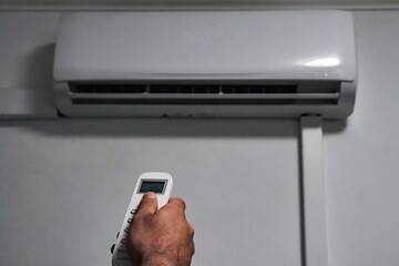 Fototapeta premium a hand of a man turning on the air-conditioning with the temperature of 26 degrees